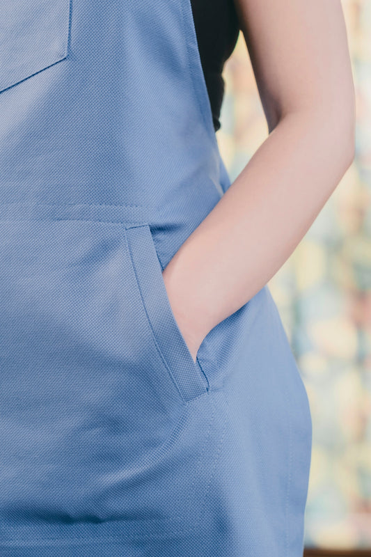 A woman wearing a blue apron and a black shirt